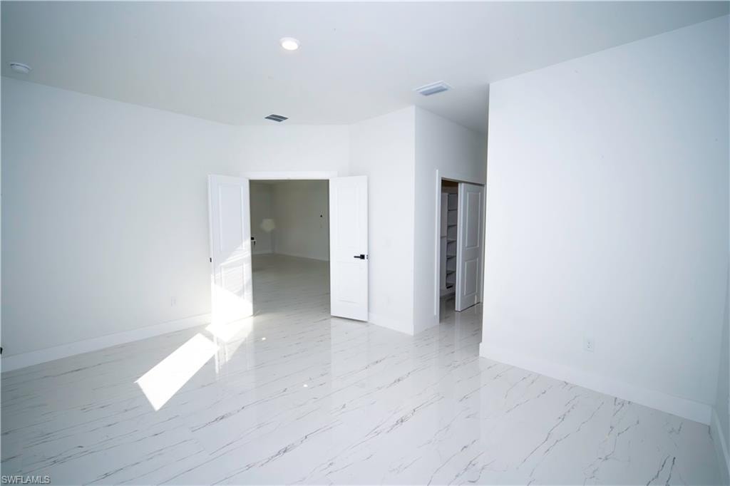 Spare room featuring baseboards and light marble finish flooring