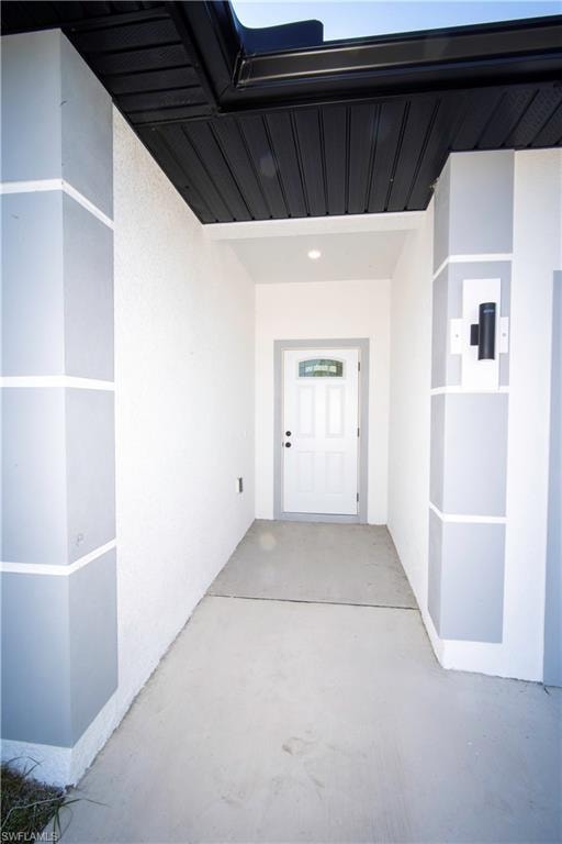 View of exterior entry featuring stucco siding and a patio area