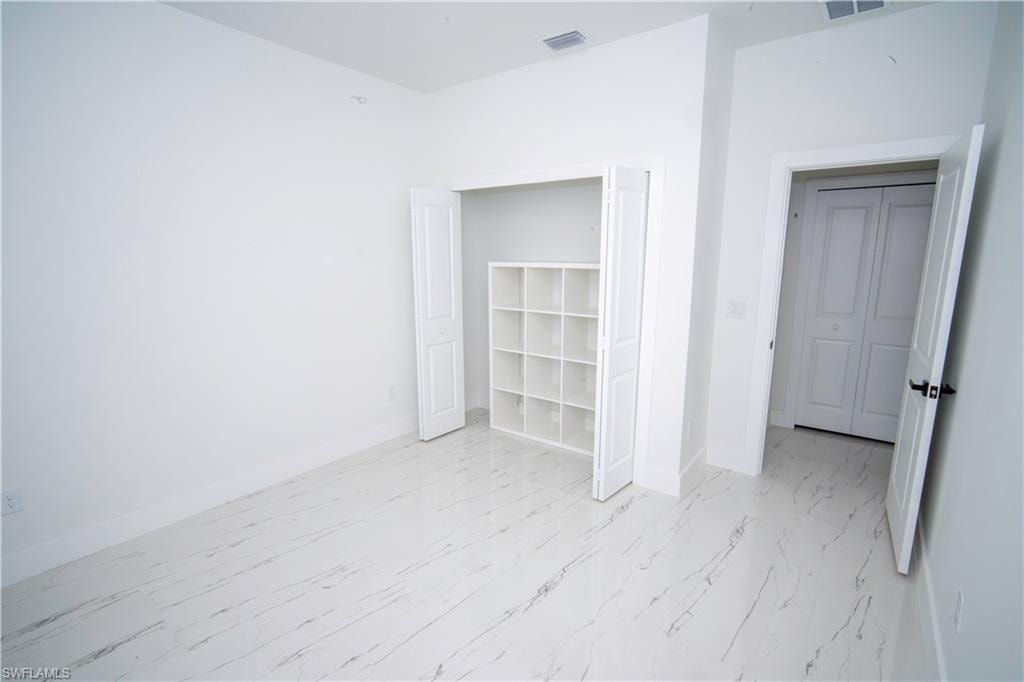 Unfurnished bedroom with baseboards and light marble finish flooring