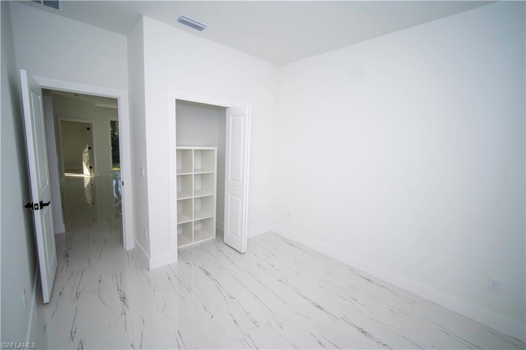 Unfurnished bedroom featuring baseboards and light marble finish flooring