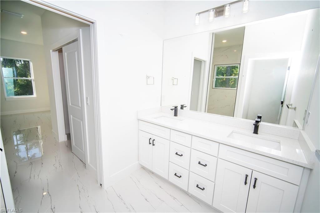 Full bathroom with double vanity and light marble finish flooring