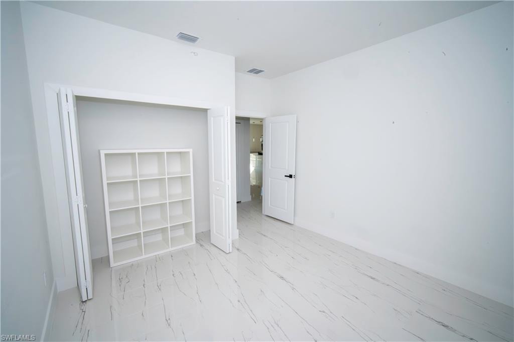 Unfurnished bedroom with light marble finish floors and a closet
