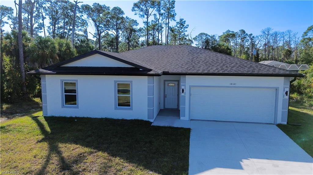 Single story home featuring a shingled roof, concrete driveway, a front yard, a garage, and stucco siding