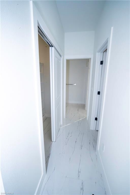 Corridor with baseboards and light marble finish floors
