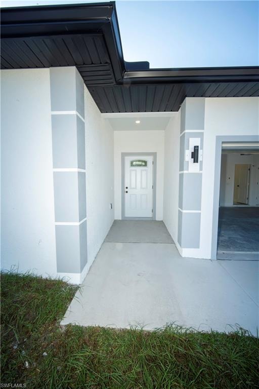 Entrance to property with stucco siding and a patio area