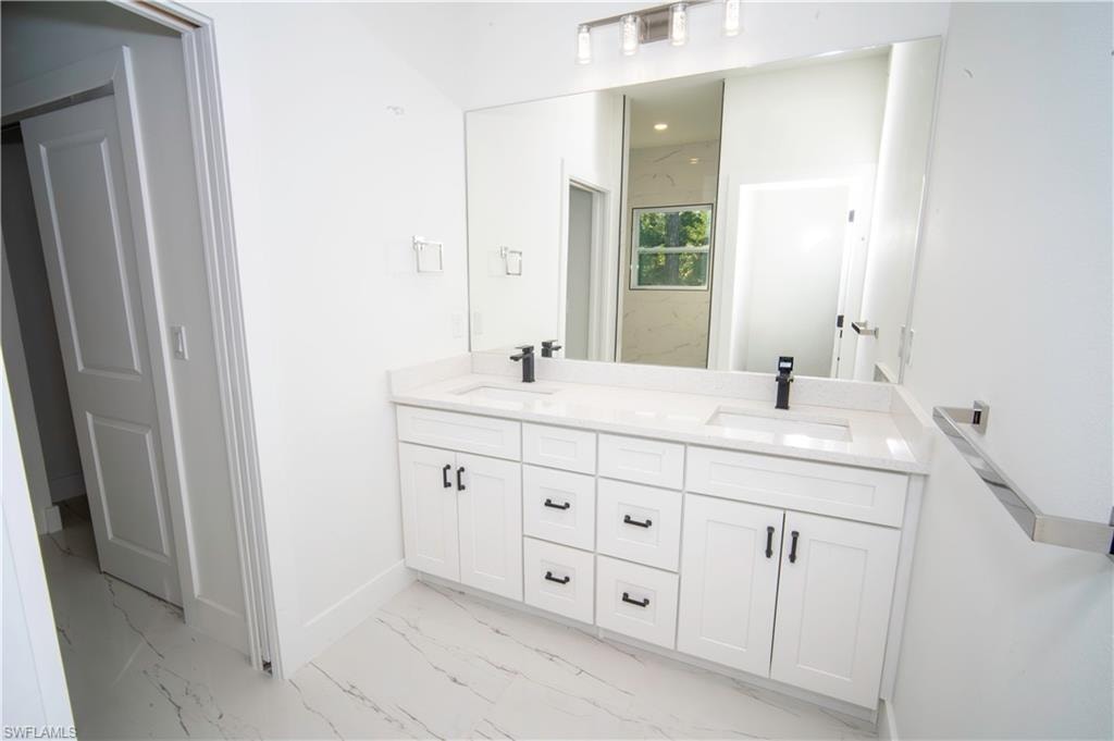 Full bath with double vanity and light marble finish flooring