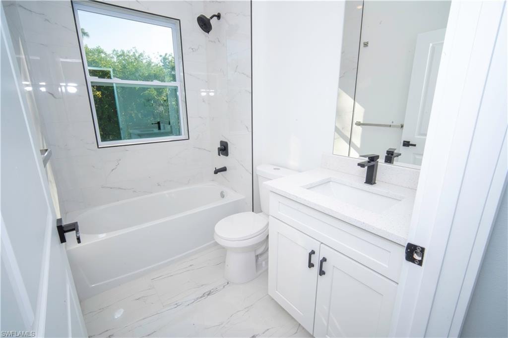 Full bathroom featuring  shower combination, vanity, and light marble finish flooring