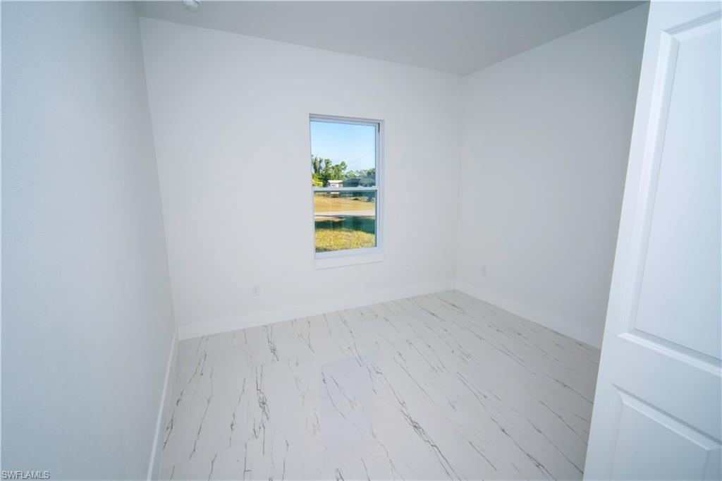 Unfurnished room with baseboards and marble look tile flooring