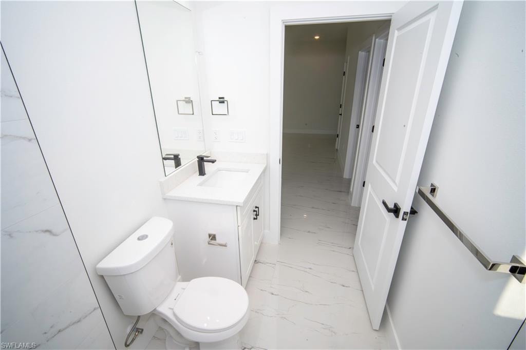 Half bath featuring vanity and light marble finish floors