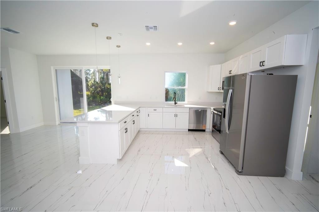 Kitchen featuring stainless steel appliances, white cabinetry, decorative light fixtures, a peninsula, and recessed lighting