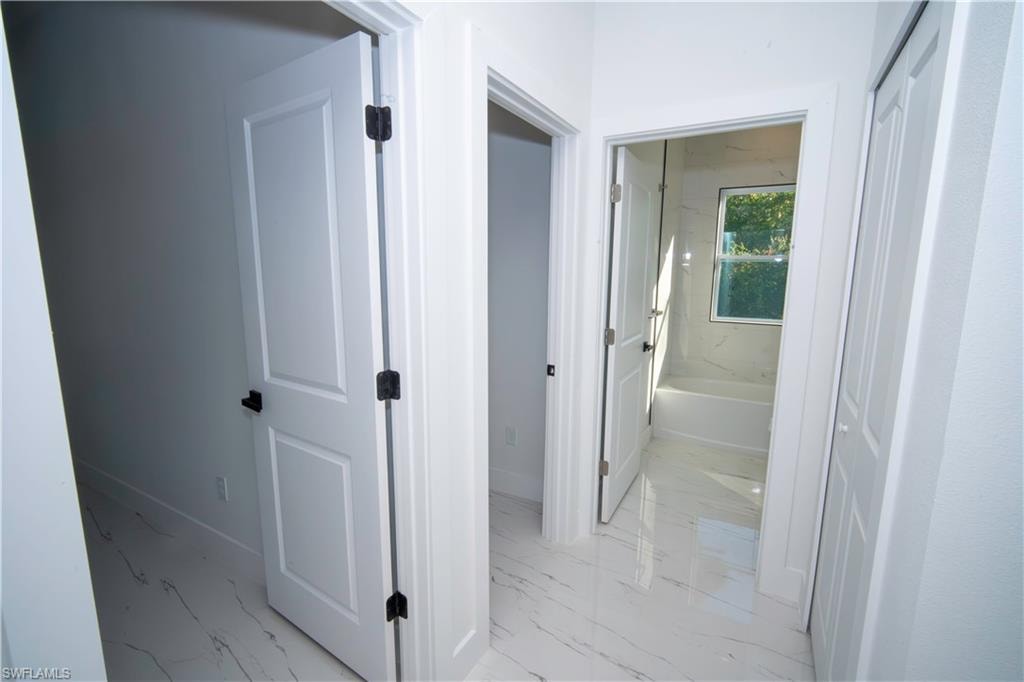 Hallway with baseboards and light marble finish floors
