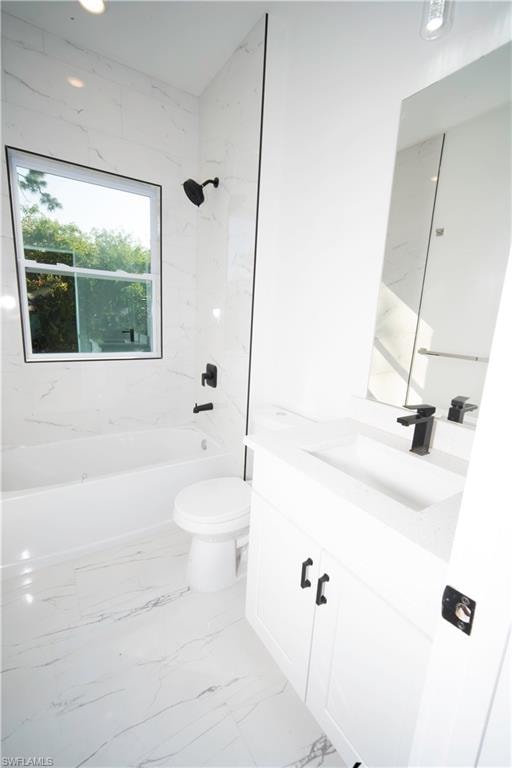 Bathroom featuring bathing tub / shower combination, vanity, and light marble finish flooring
