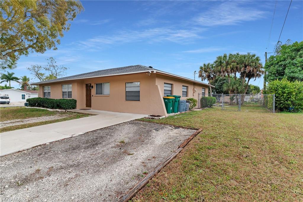 View of property exterior with stucco siding, a gate, and driveway