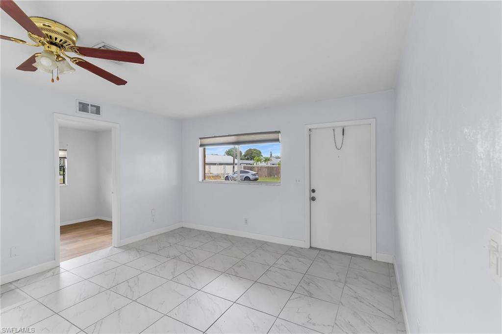 Empty room featuring light marble finish floors and ceiling fan