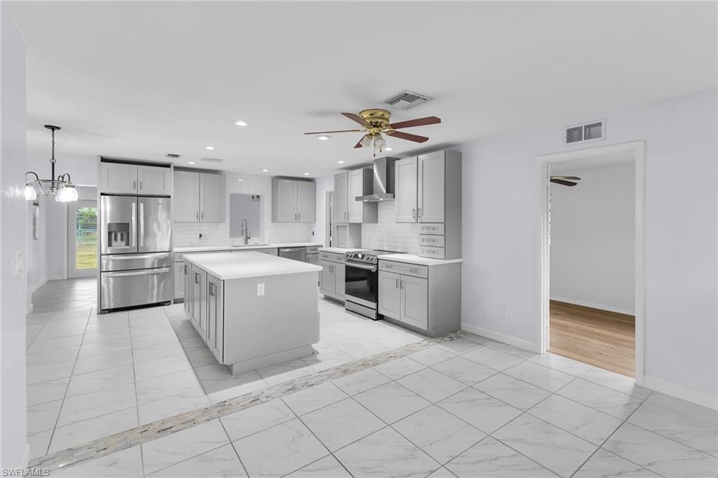 Kitchen with light marble finish flooring, stainless steel appliances, light countertops, backsplash, and a kitchen island