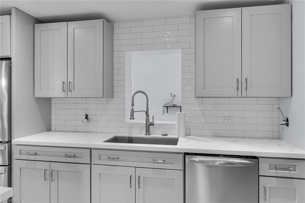 Kitchen featuring appliances with stainless steel finishes, light stone counters, and decorative backsplash