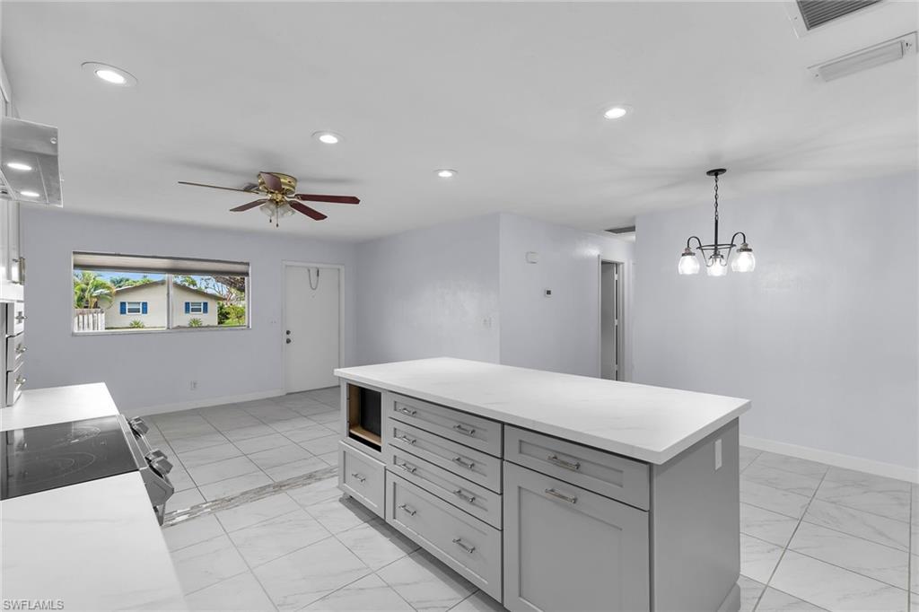 Kitchen featuring recessed lighting, a center island, hanging light fixtures, gray cabinets, and range with electric cooktop