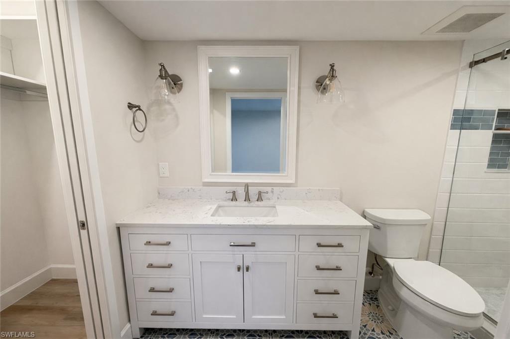 Bathroom with tiled shower, vanity, and a walk in closet