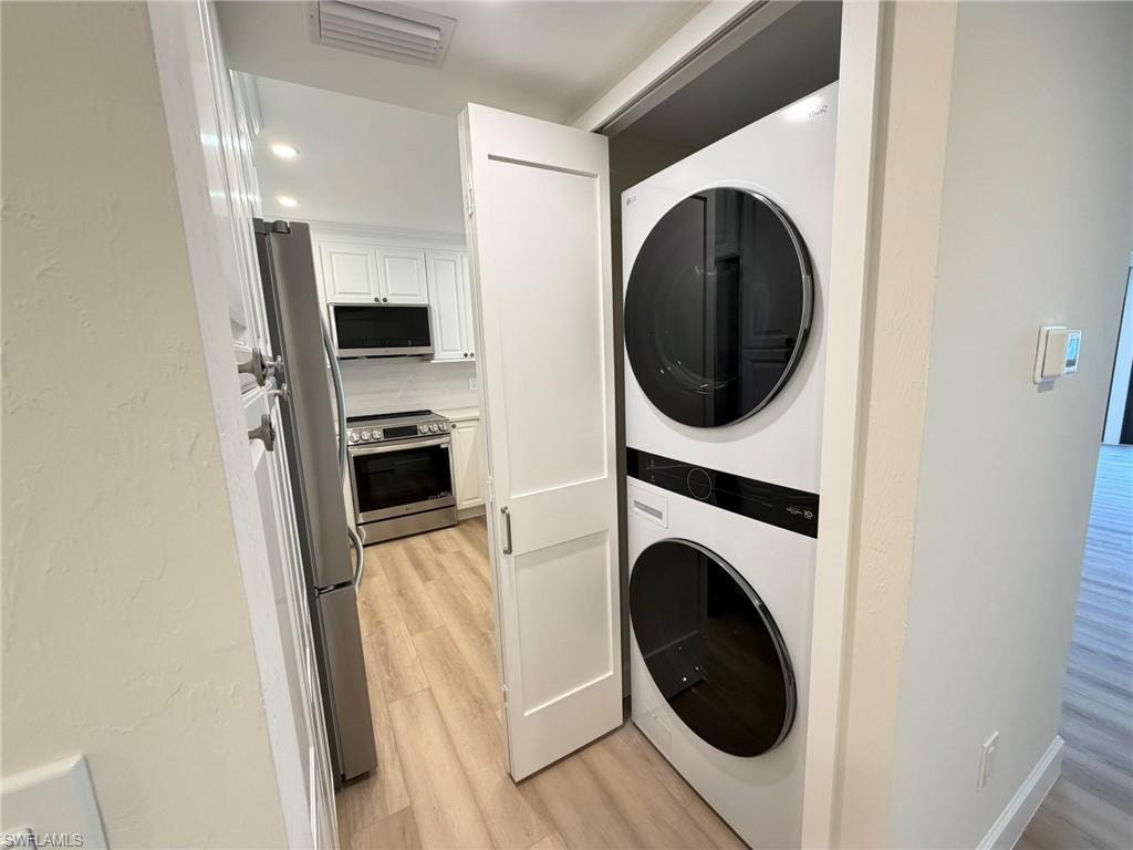 Laundry area with estacked washer and dryer, light wood-style floors, recessed lighting, and a textured wall