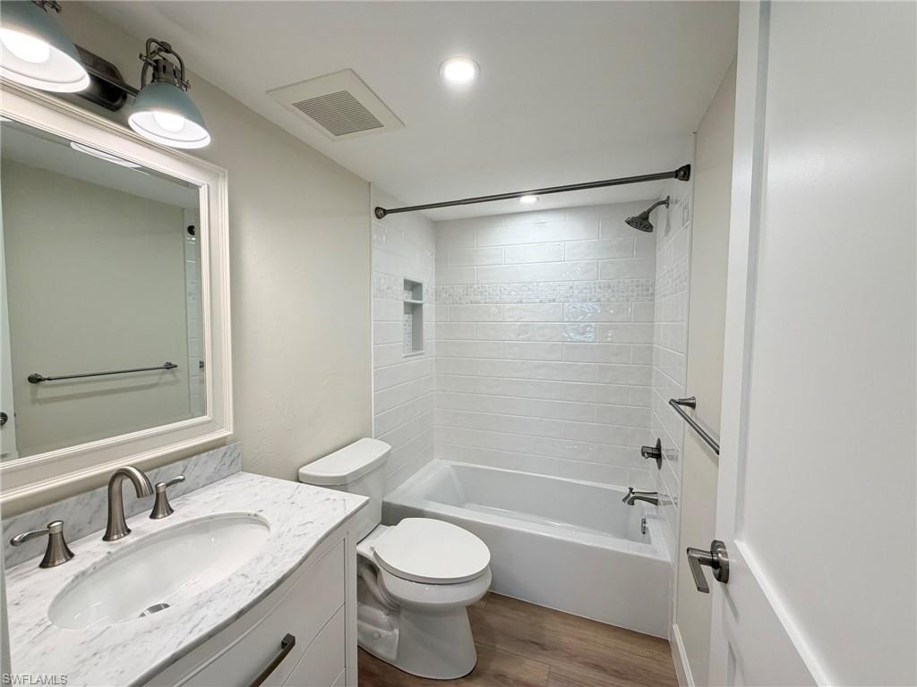 Bathroom featuring bathtub / shower combination, vanity, dark wood-type flooring, and recessed lighting