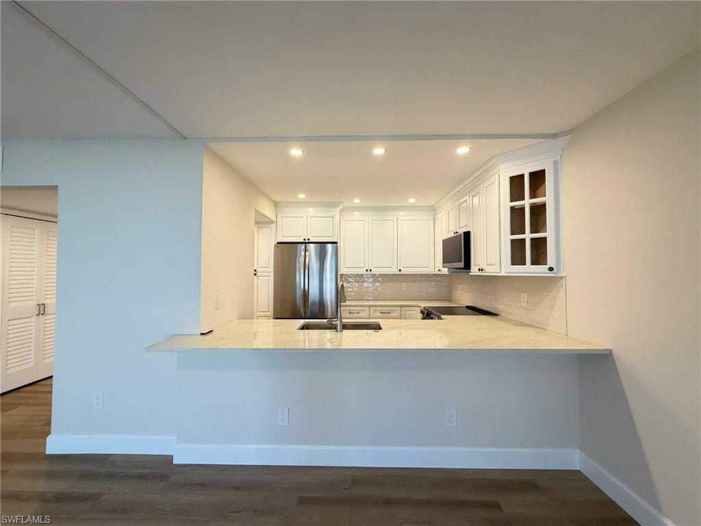 Kitchen with white cabinetry, stainless steel appliances, recessed lighting, decorative backsplash, and dark wood-style floors