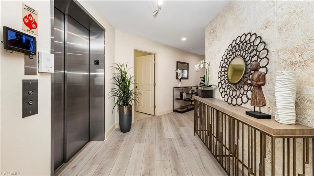Hall featuring elevator, light wood-style flooring, and recessed lighting