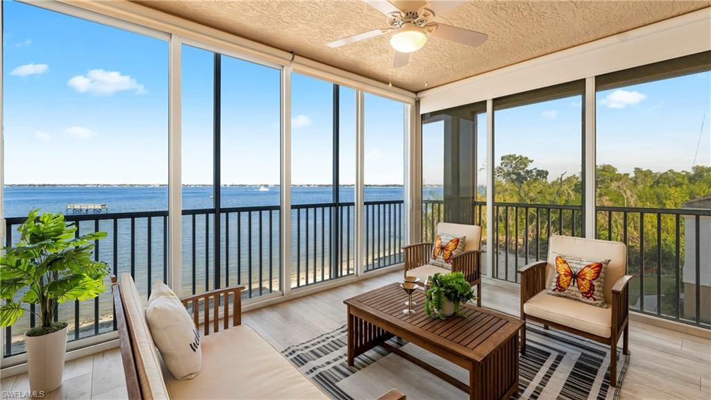 Sunroom featuring floor to ceiling windows, hardwood / wood-style flooring, a water view, and a textured ceiling