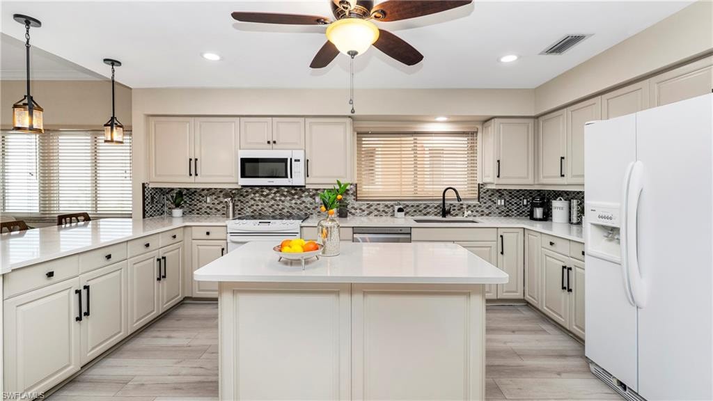 Kitchen featuring white appliances, plenty of natural light, hanging light fixtures, light stone counters, and recessed lighting