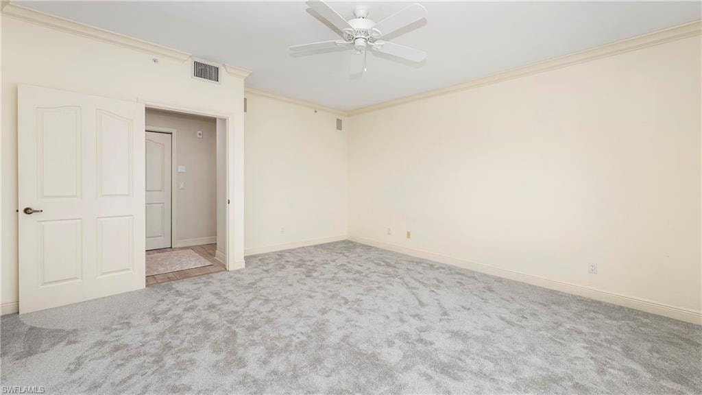Spare room featuring crown molding, light colored carpet, and a ceiling fan