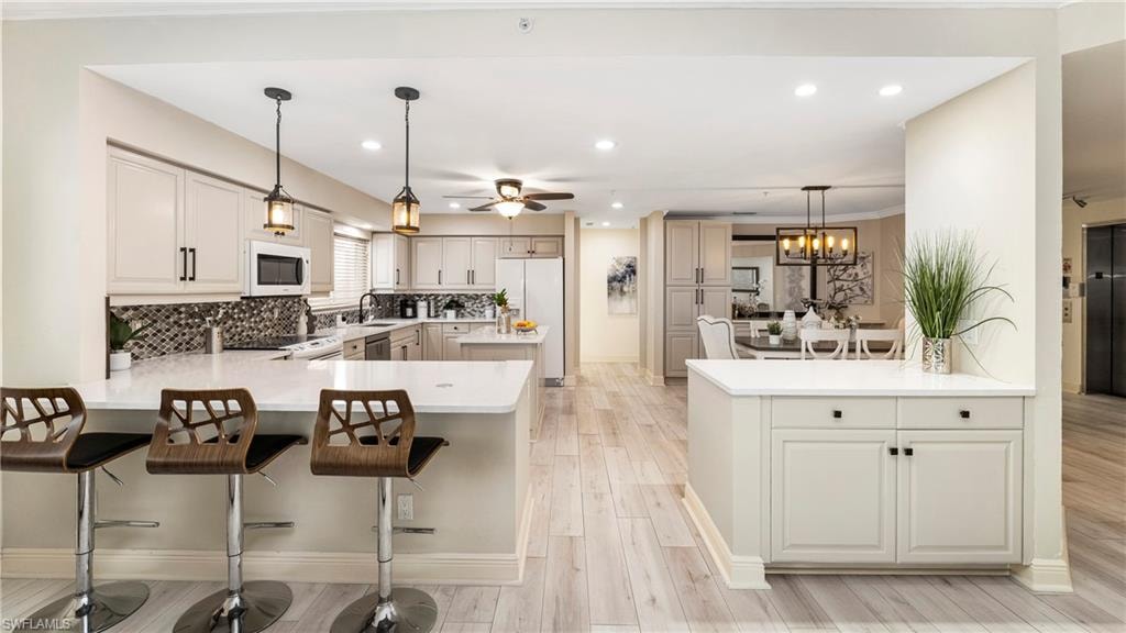 Kitchen featuring a peninsula, pendant lighting, a kitchen breakfast bar, tasteful backsplash, and recessed lighting