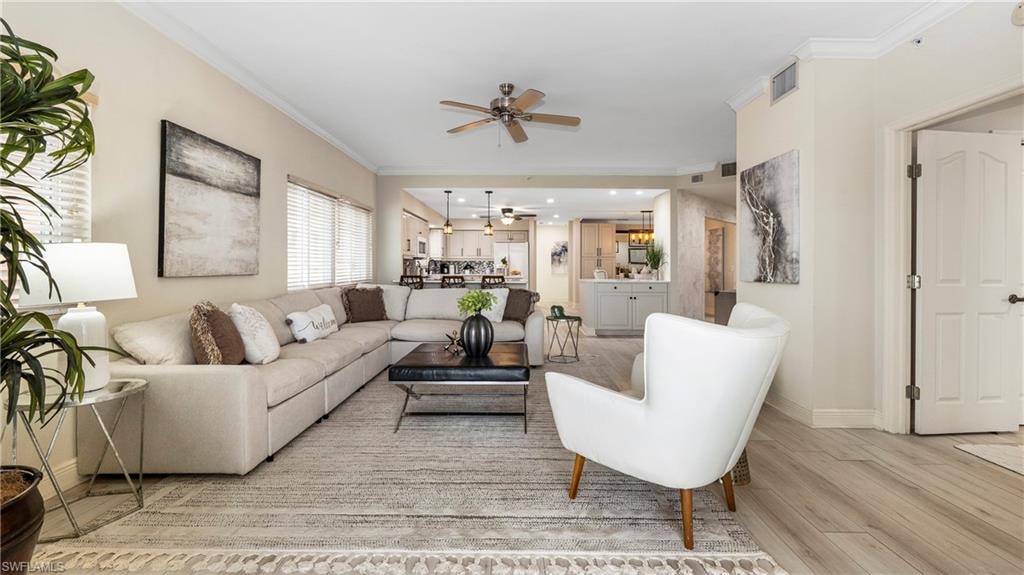 Living area with crown molding, light wood-style flooring, ceiling fan, and recessed lighting