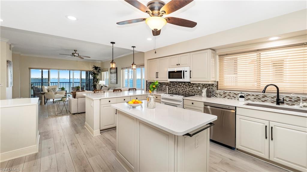 Kitchen with open floor plan, a peninsula, hanging light fixtures, ceiling fan, and white appliances