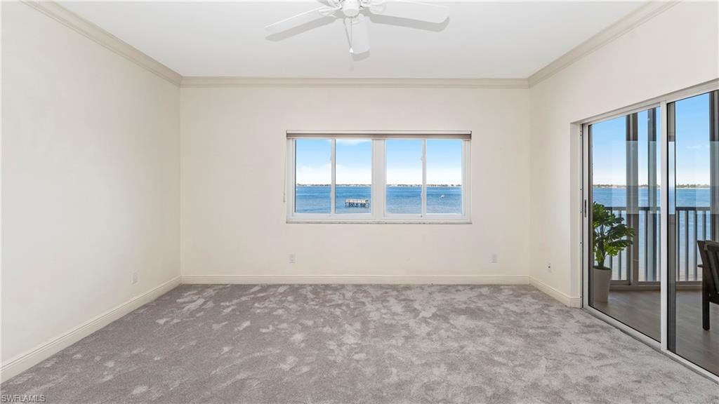Unfurnished room with carpet floors, crown molding, a water view, and a ceiling fan