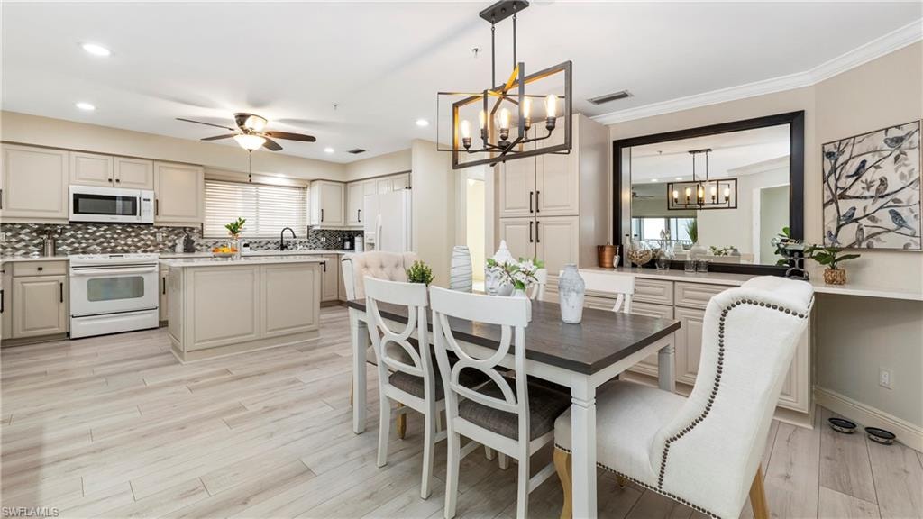 Dining room with a chandelier, light wood-style floors, plenty of natural light, a ceiling fan, and recessed lighting