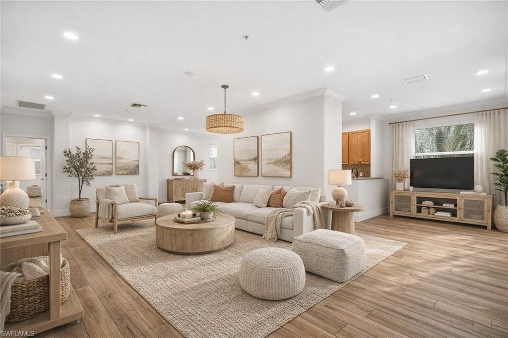 Living room featuring light wood-style floors, recessed lighting, and crown molding