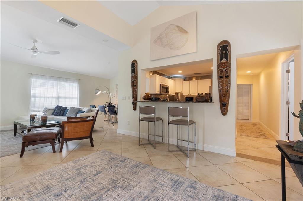 Living area featuring light tile patterned floors, a ceiling fan, high vaulted ceiling, and recessed lighting