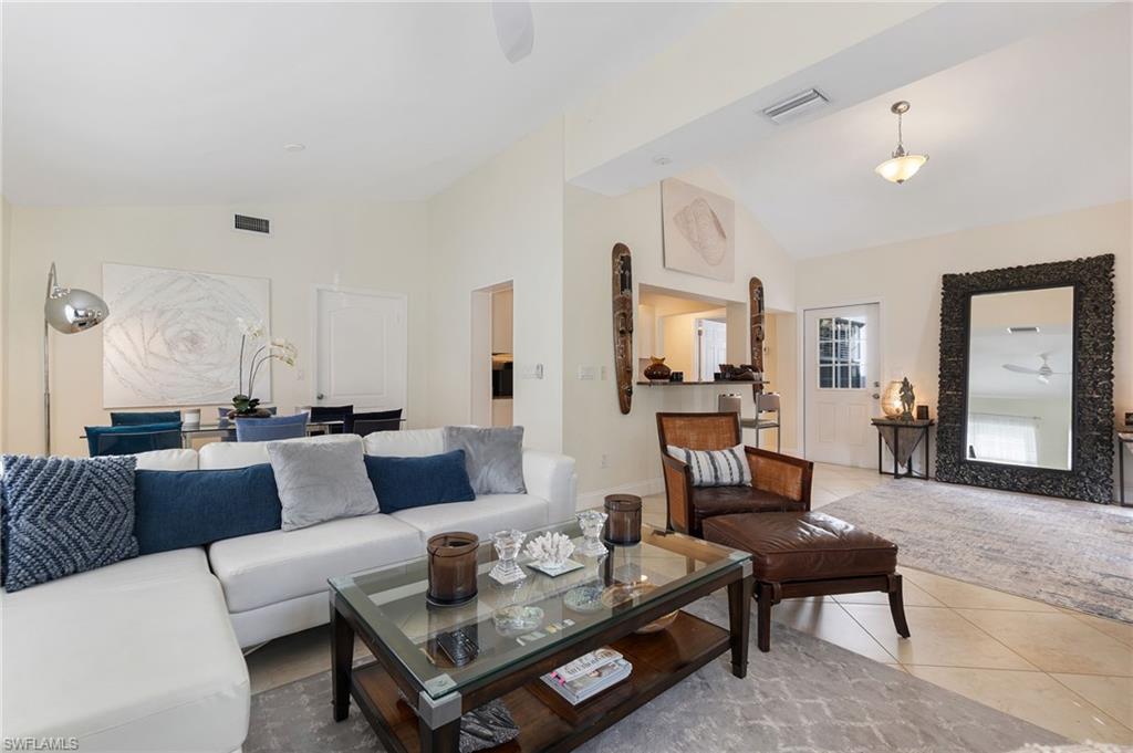 Living room with a ceiling fan, tile patterned flooring, and high vaulted ceiling