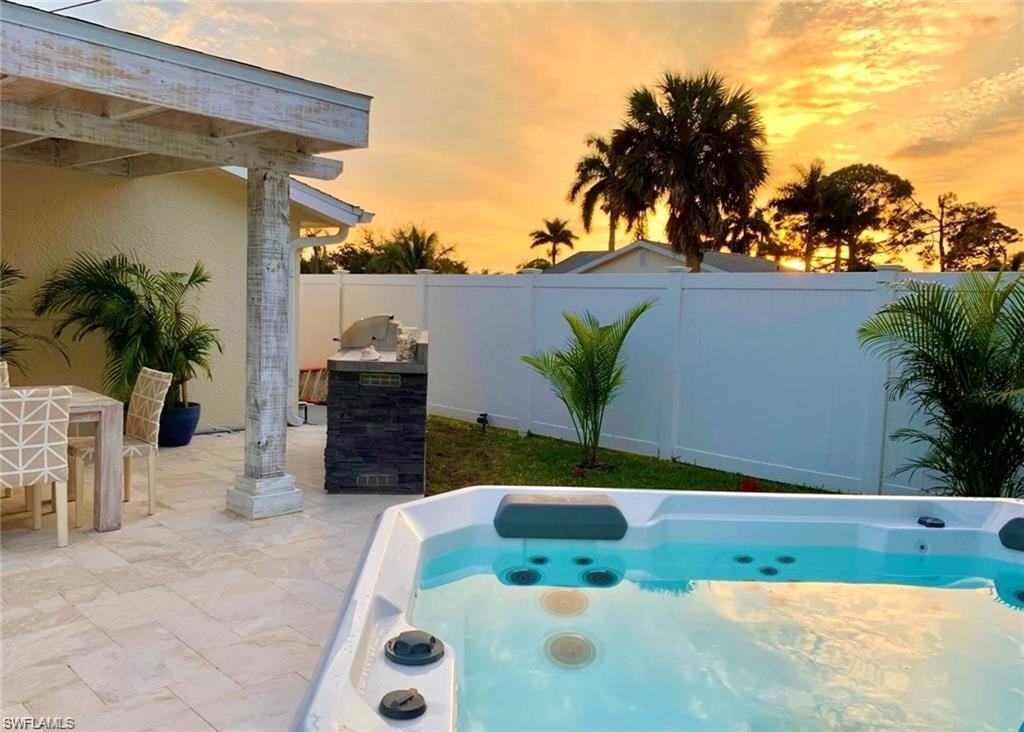 Pool at dusk with a hot tub, a patio area, a fenced backyard, and outdoor dining space