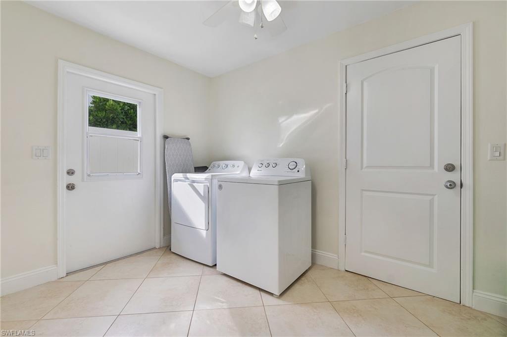 Washroom featuring washing machine and dryer, light tile patterned flooring, and a ceiling fan