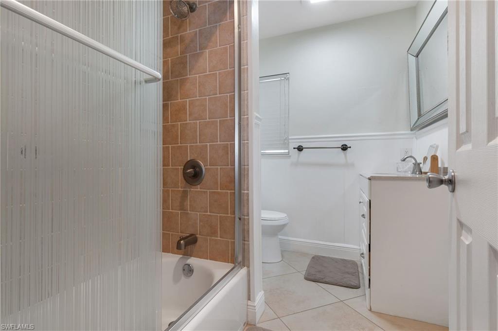 Bathroom featuring vanity, shower / bath combination with glass door, and light tile patterned flooring