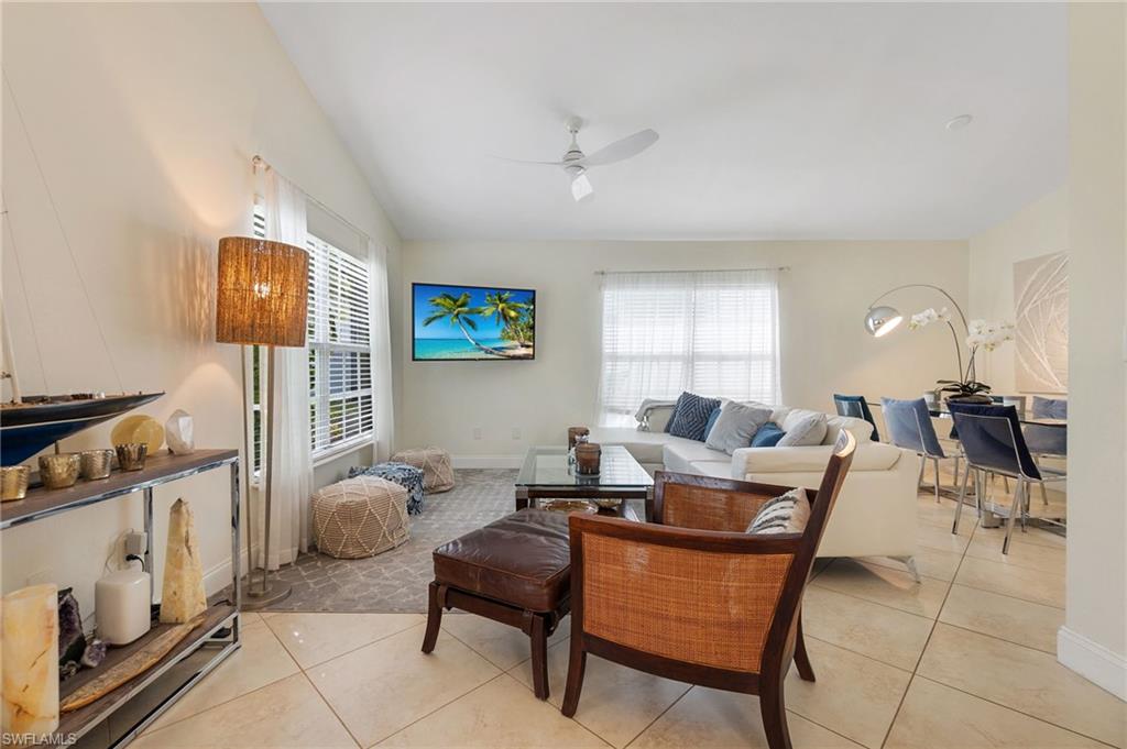 Living room with light tile patterned floors, plenty of natural light, a ceiling fan, and lofted ceiling