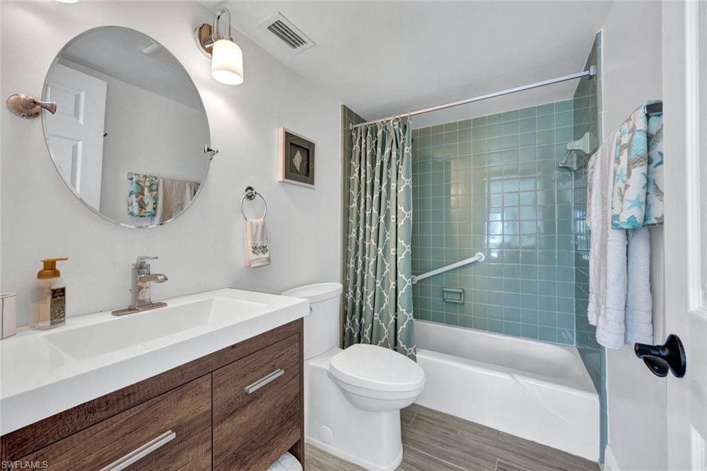 Bathroom with vanity, shower / bath combo, and light wood finished floors