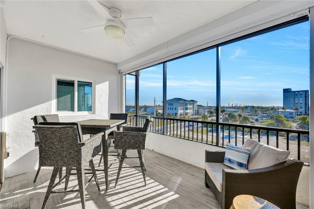 Sunroom / solarium featuring a ceiling fan, outdoor dining space, and a balcony