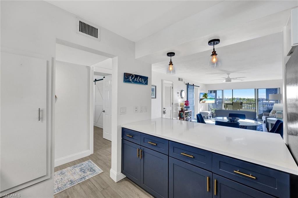 Kitchen with a barn door, open floor plan, pendant lighting, blue cabinets, and ceiling fan