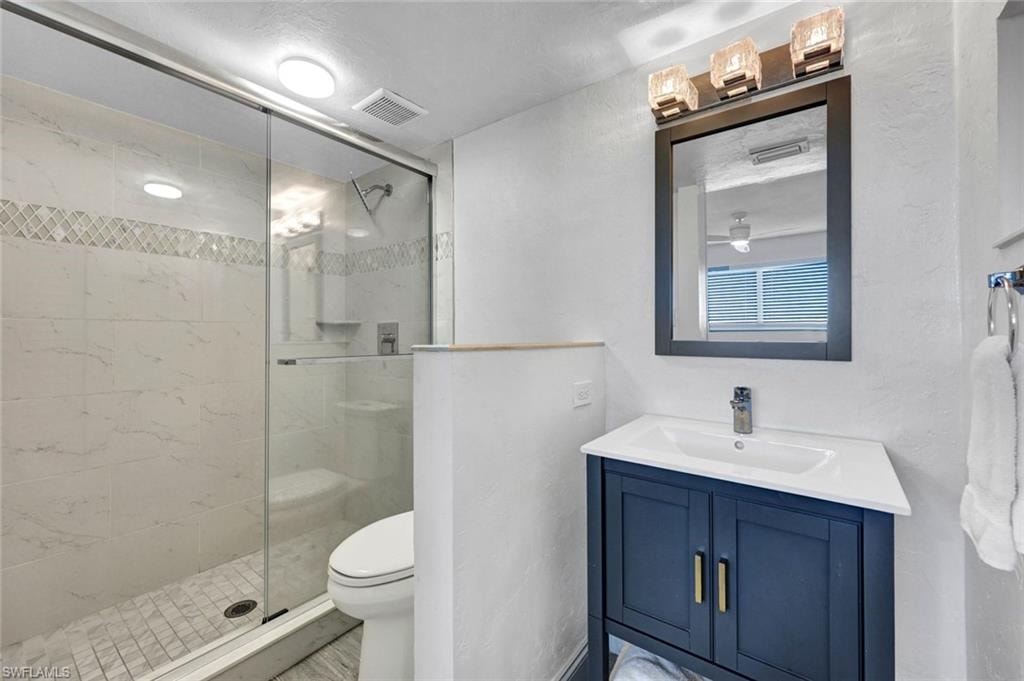 Full bathroom with vanity, a stall shower, and a textured wall