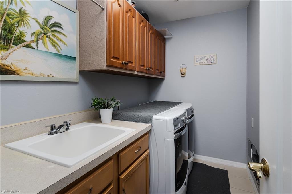 Laundry room with washing machine and clothes dryer, cabinet space, and light tile patterned flooring