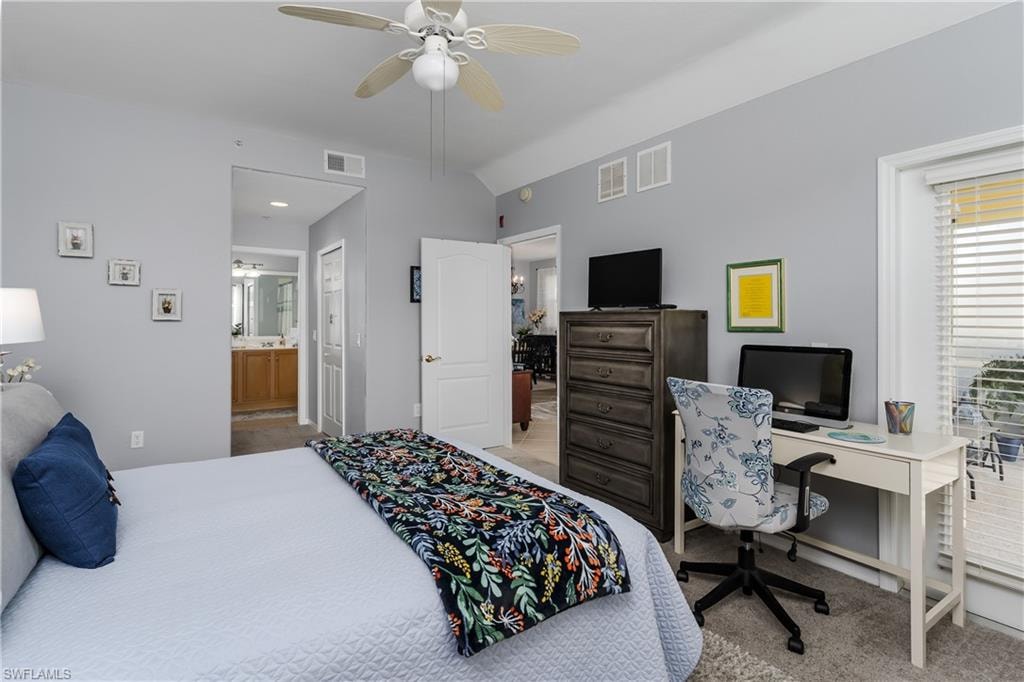 Bedroom featuring vaulted ceiling, ensuite bath, ceiling fan, and light colored carpet