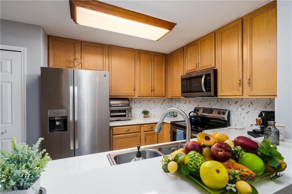 Kitchen featuring light countertops, stainless steel appliances, wood finish cabinets, and tasteful backsplash