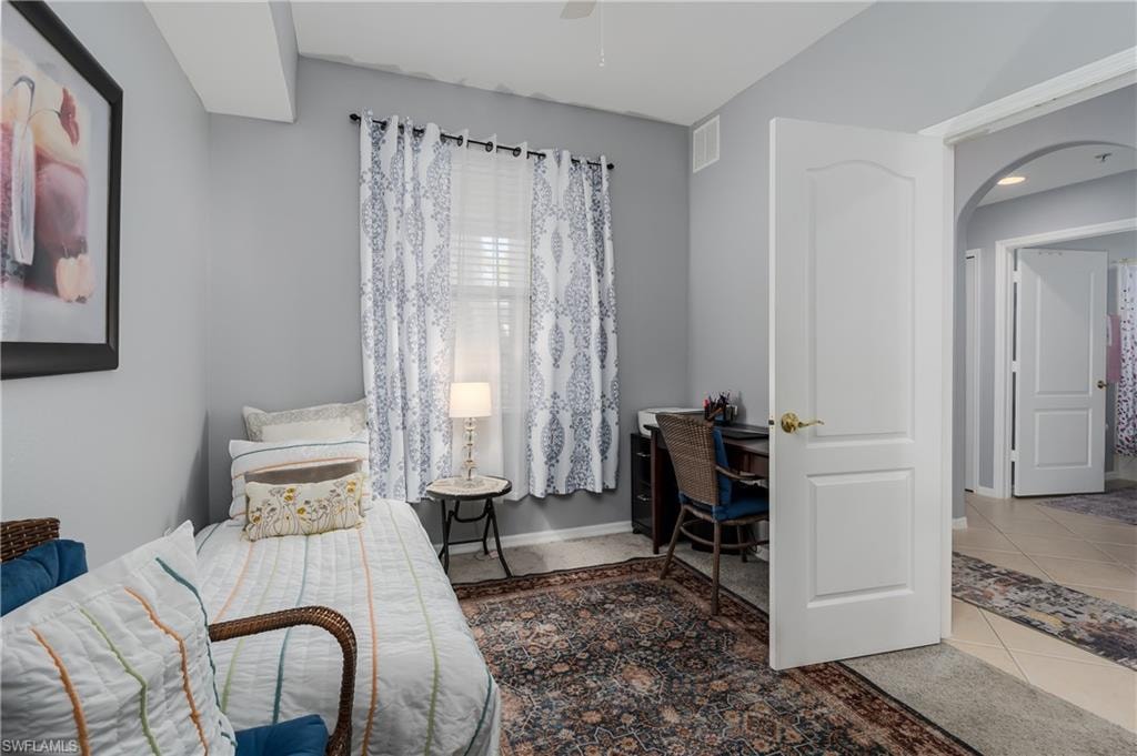 Tiled bedroom featuring arched walkways and an office area