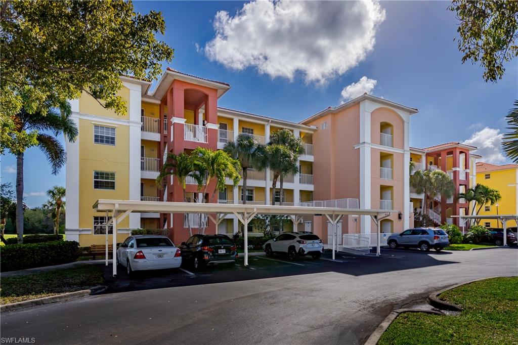 View of apartment building / complex featuring covered parking